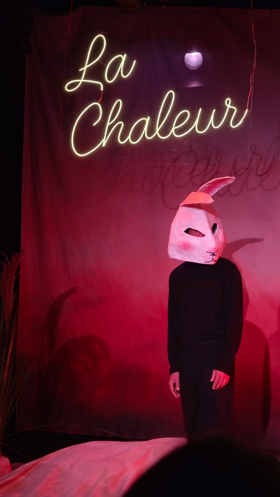 Le personnage du lapin sur scène, sous l'enseigne lumineuse La Chaleur, lumière rose