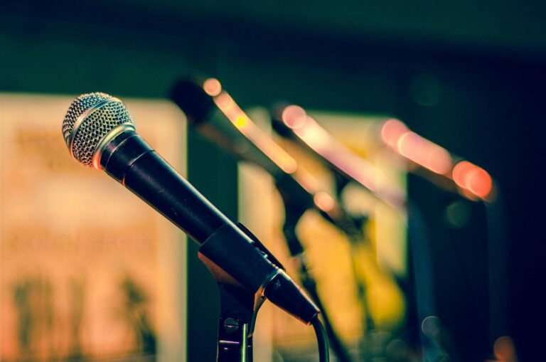 Microphones sur pied alignés devant une scène aux lumières tamisées