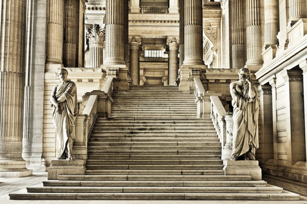 Grand escalier de pierre bordé de colonnes et de statues dans le hall du palais de justice de Bruxelles