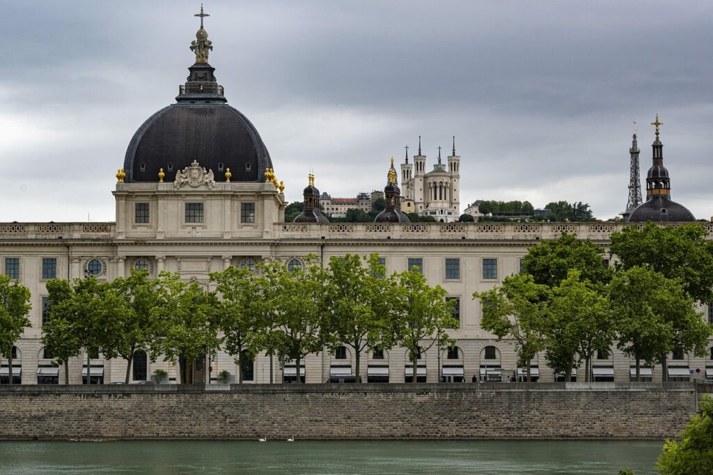 Le dôme et la façade du Grand Hôtel-Dieu de Lyon au bord du Rhône, sous un ciel nuageux