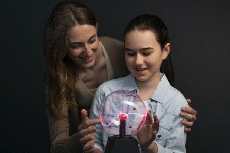 Une femme et une fillette posent les mains sur une boule plasma lumineuse dans une salle sombre