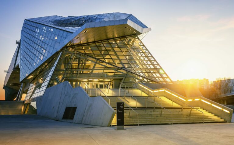Le musée des Confluences à Lyon, architecture de verre et d'acier aux facettes réfléchissantes, photographié en contre-plongée au coucher du soleil