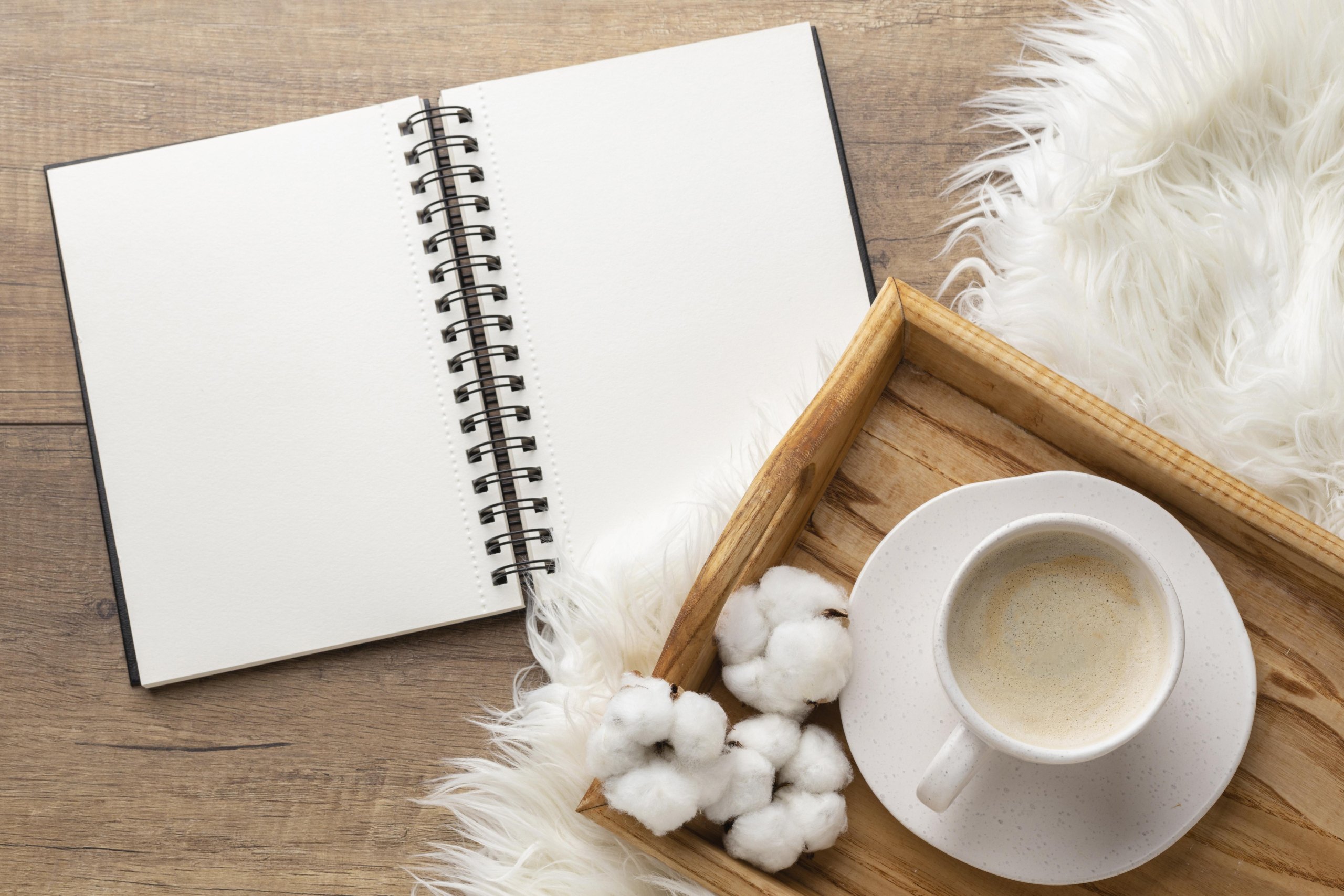 Carnet ouvert, tasse de café et fleurs de coton sur un plateau