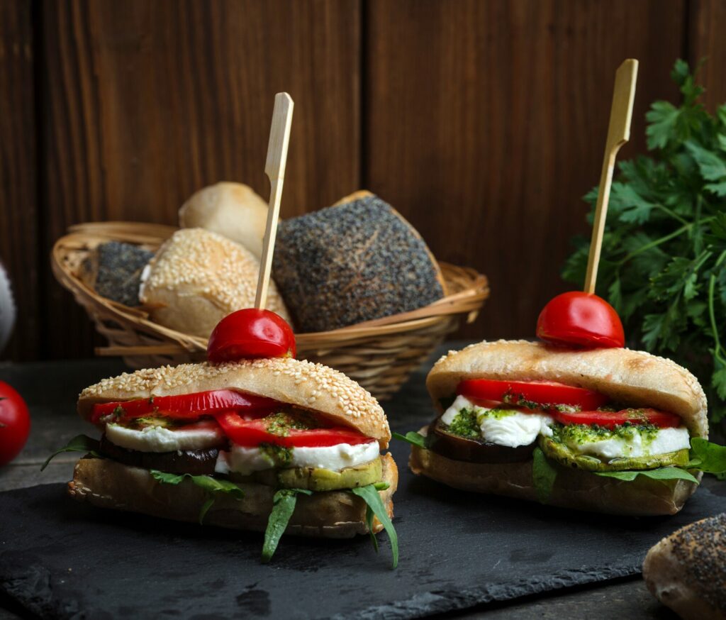 Sandwichs garnis de mozzarella, de tomate et de salade posés sur une ardoise