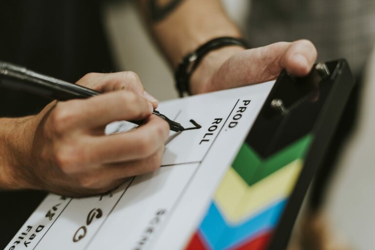 Gros plan sur des mains qui remplissent au feutre un clap de cinéma sur un plateau de tournage