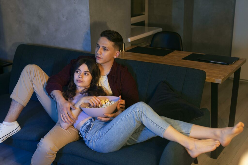 Couple installé dans un canapé devant une série en streaming