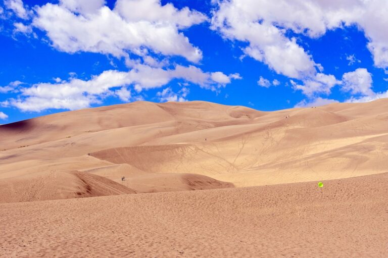 Dunes de sable ondulées sous un ciel bleu chargé de nuages blancs, au parc national des Great Sand Dunes, dans le Colorado