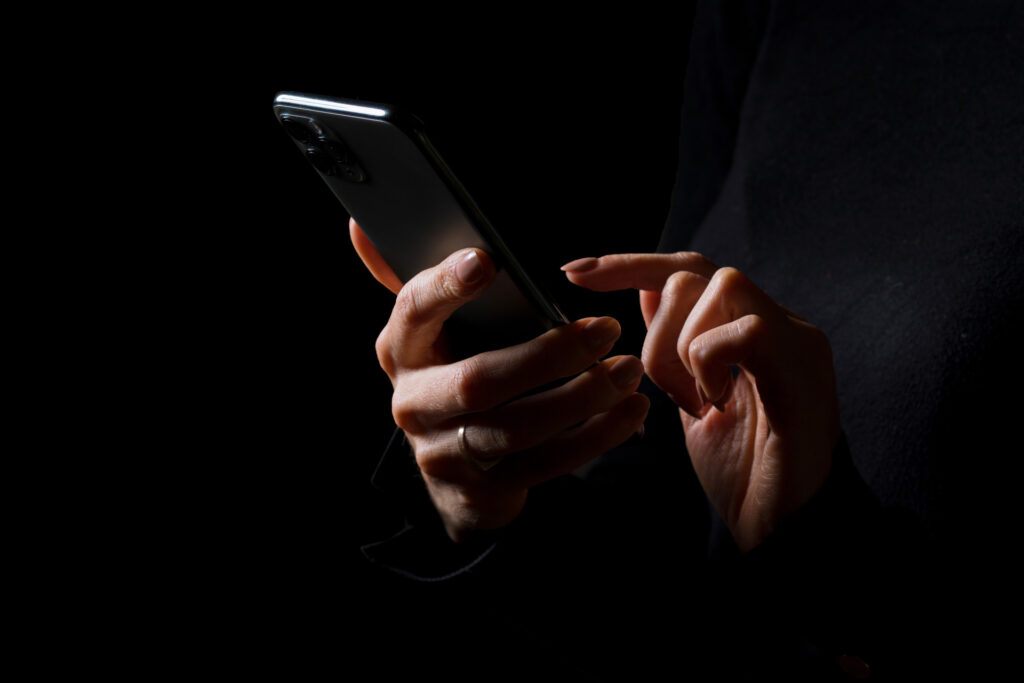 Mains tenant un téléphone dans la pénombre