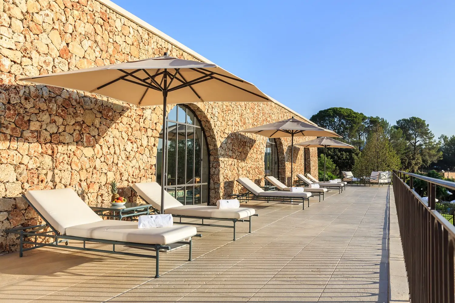 Transats et parasols sur la terrasse de pierre sèche du Château de Berne