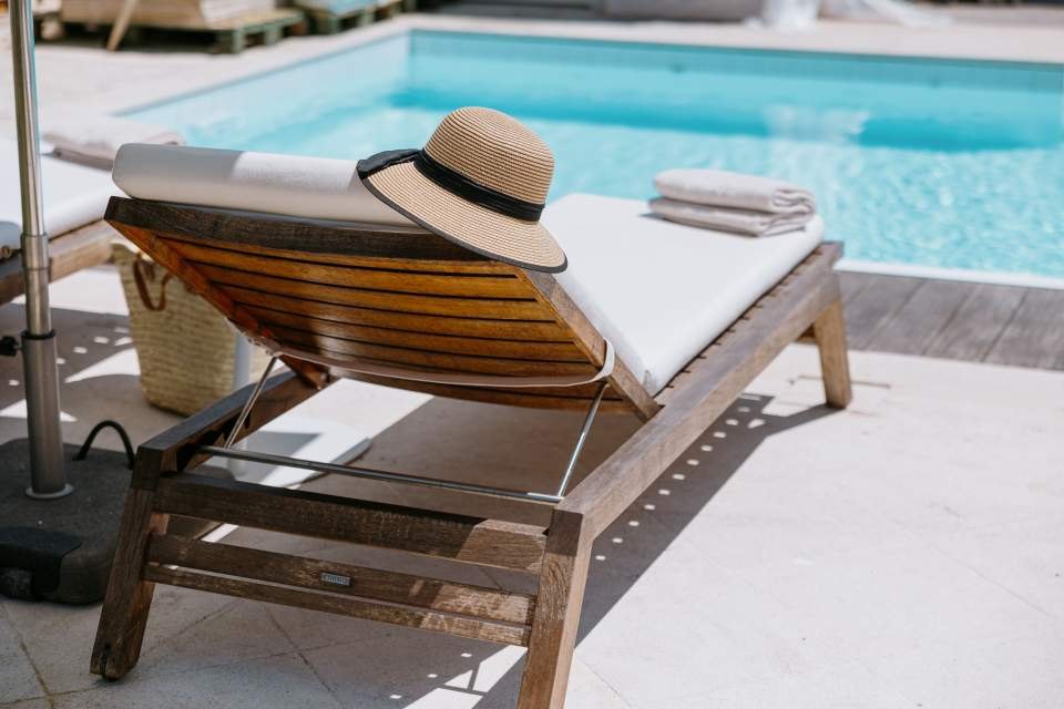 Transat et chapeau de paille au bord de la piscine