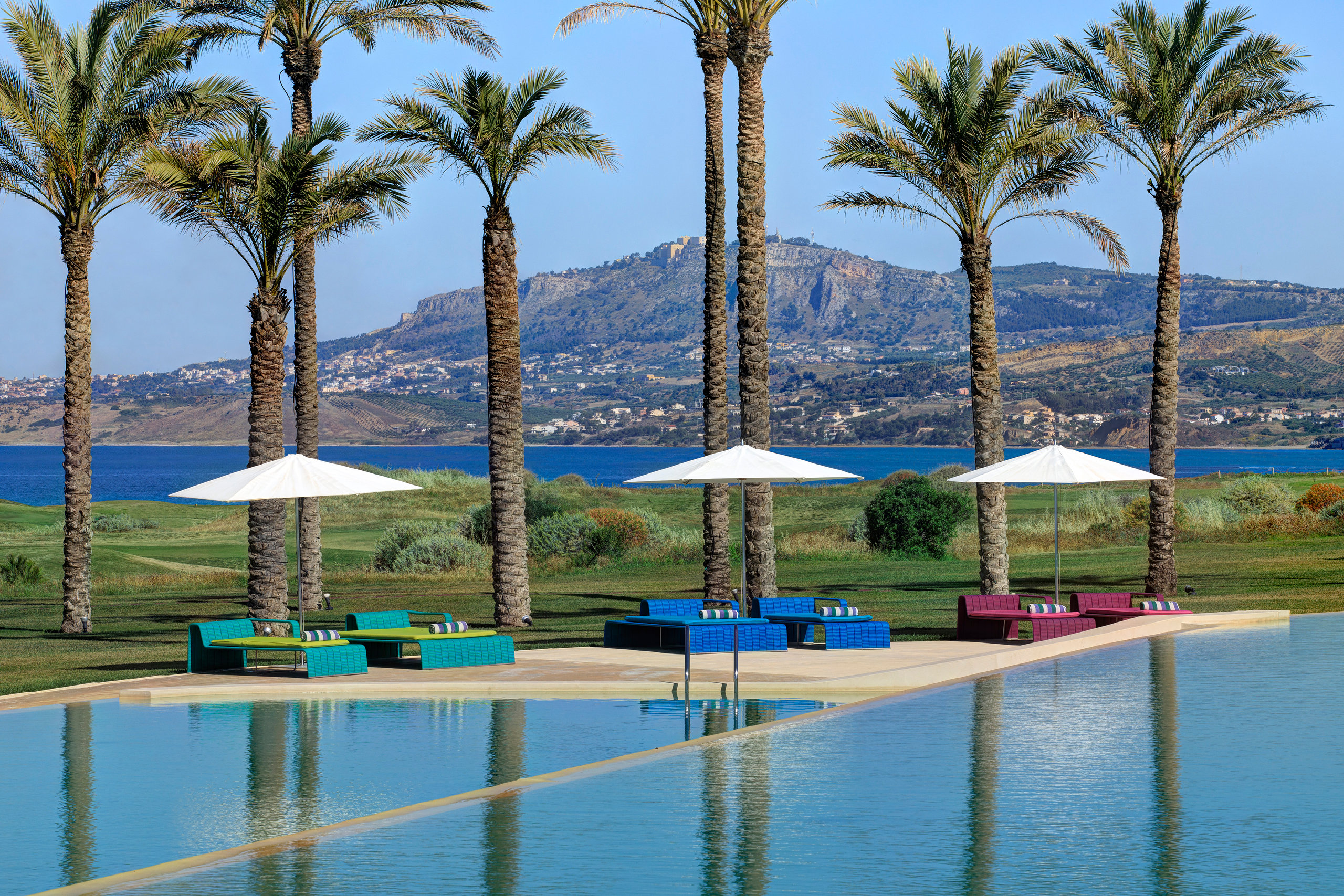 Piscine à débordement bordée de palmiers du Verdura Resort, en Sicile