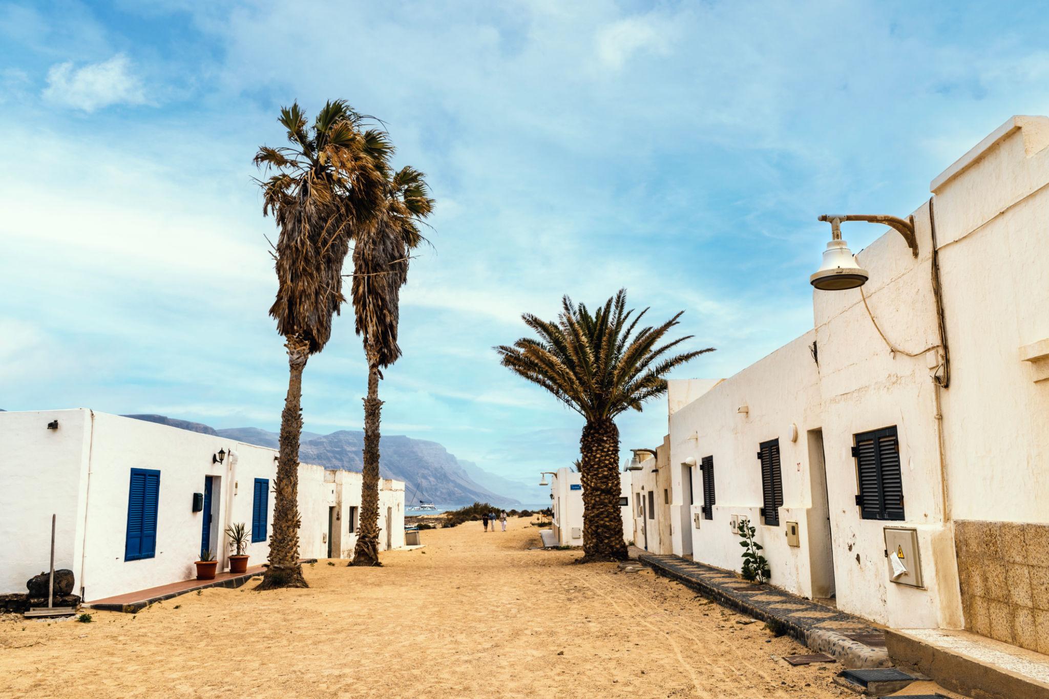 Rue de sable bordée de maisons blanches et de palmiers à Caleta de Sebo, La Graciosa
