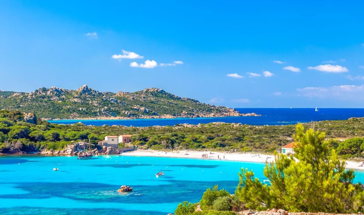 Crique de sable blanc et eaux turquoise bordée de maquis en Sardaigne