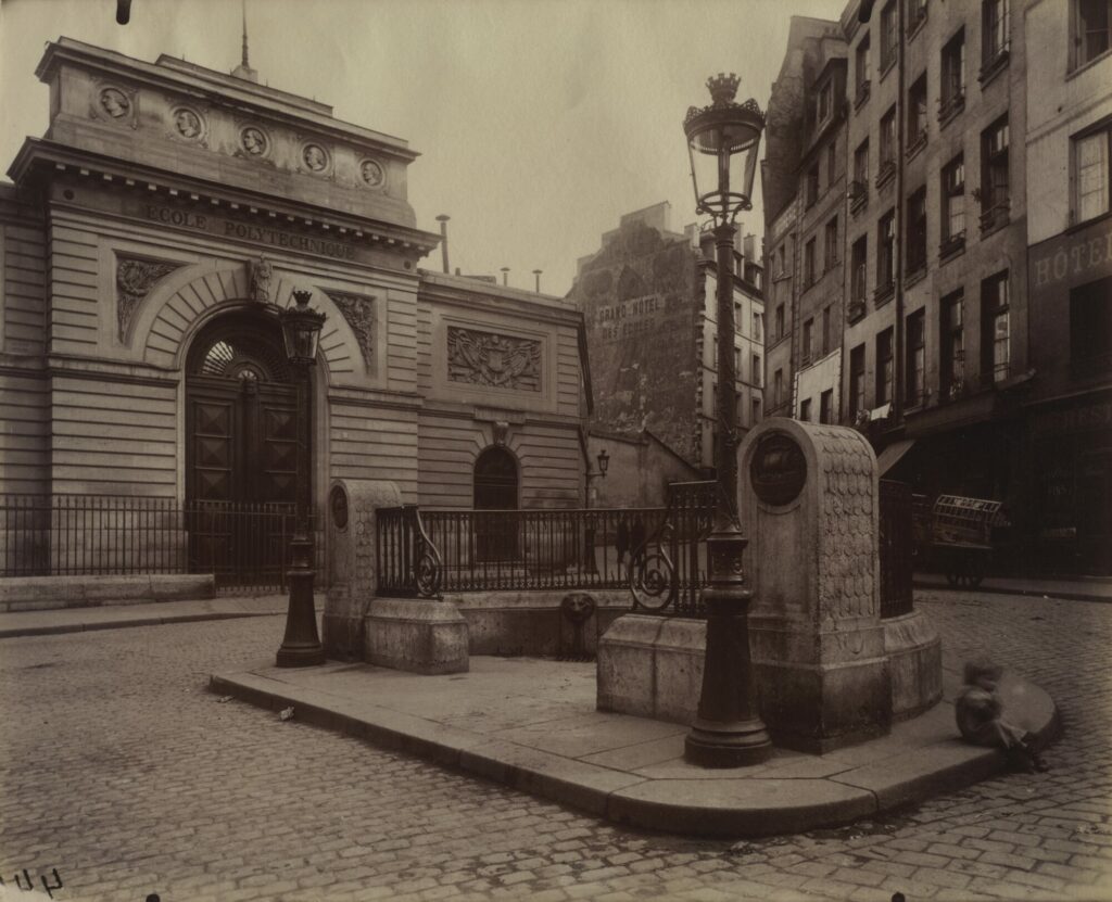 Placette pavée du Quartier latin photographiée par Eugène Atget en 1902, avec une fontaine-borne et un réverbère devant le portail de l'École polytechnique