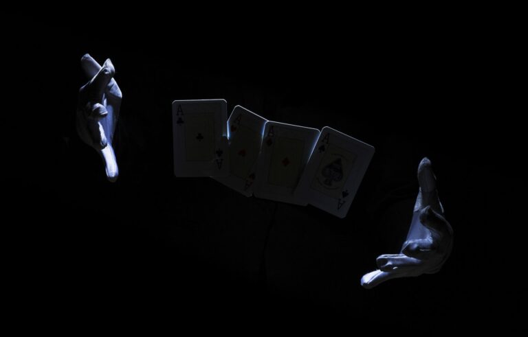 Main d’un magicien exécutant un tour avec une carte à jouer sur fond noir