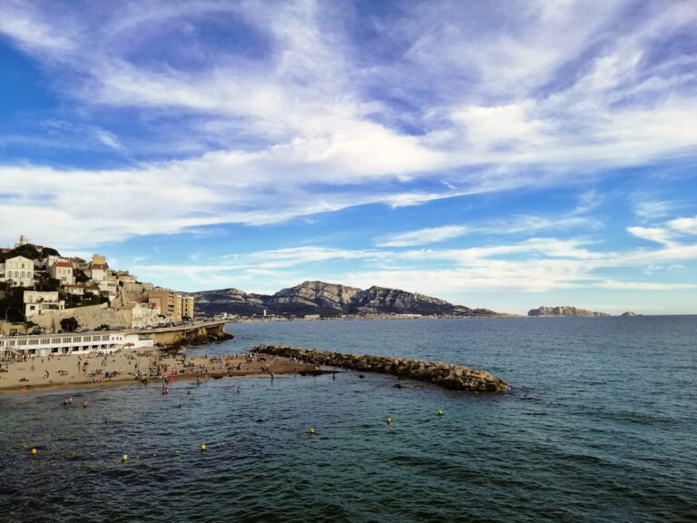Littoral rocheux de Marseille sous un ciel nuageux, avec la mer Méditerranée et des collines au loin