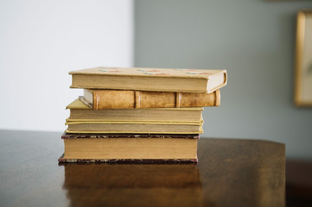 Pile de livres anciens aux reliures usées posée sur un meuble en bois
