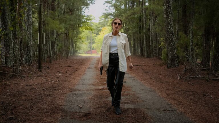 Jessica Chastain, en lunettes de soleil et chemise blanche, marche sur un chemin forestier dans le film Heartland