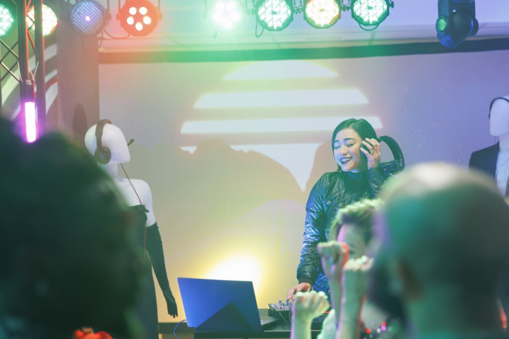 Un DJ mixe sur scène sous des projecteurs colorés, devant un public dans la pénombre