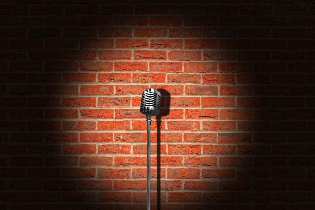 Microphone rétro sur pied éclairé par un projecteur devant un mur de briques