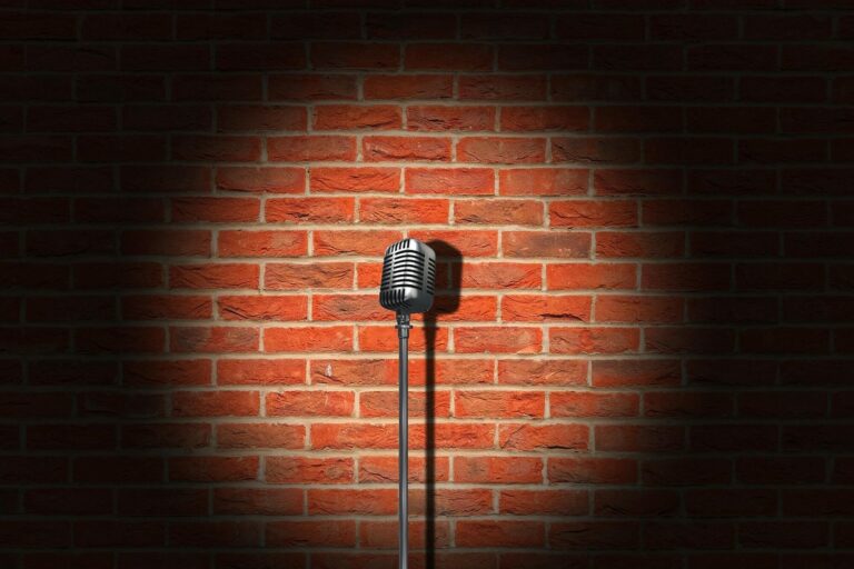 Microphone rétro sur pied éclairé par un projecteur devant un mur de briques
