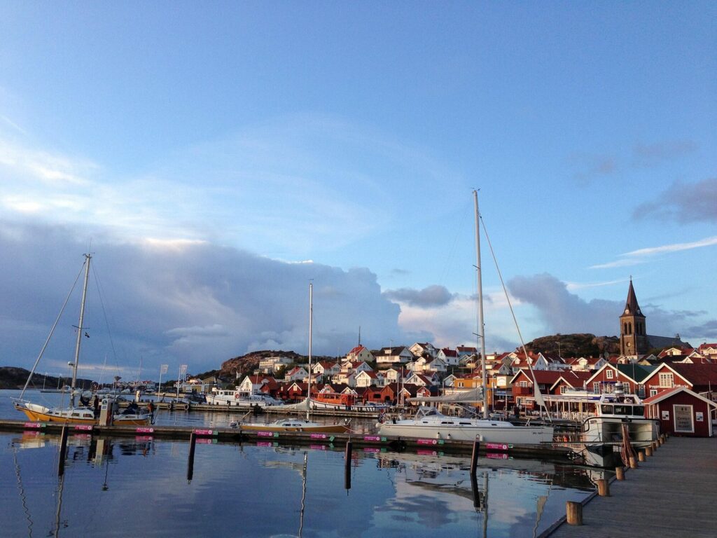 Port de plaisance de Fjällbacka au crépuscule, avec ses voiliers et ses maisons au pied de la falaise