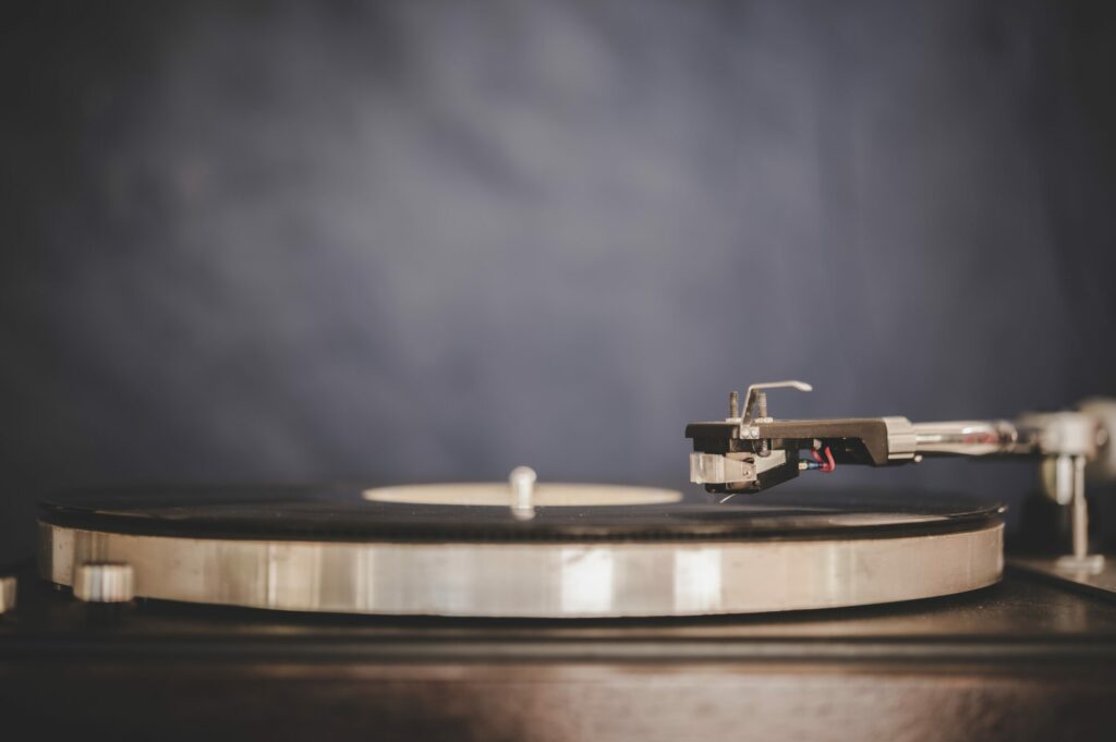 Platine vinyle argentée avec un disque noir posé sur le plateau, sur fond gris sombre
