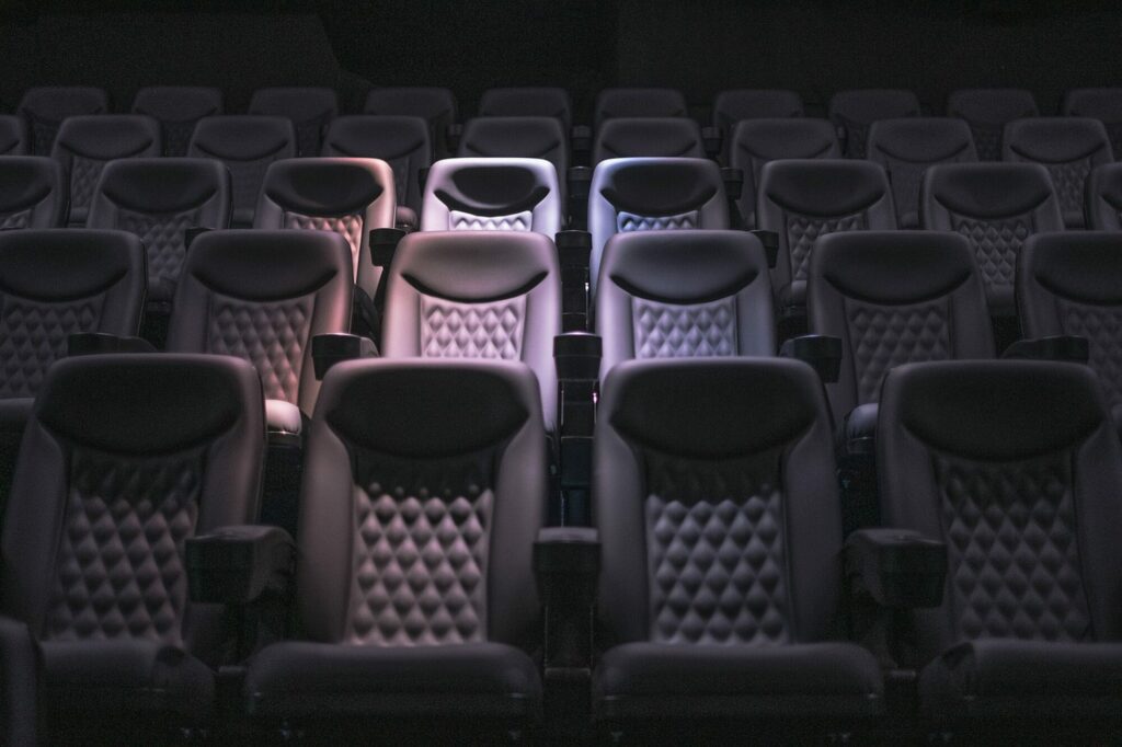 Rangées de fauteuils vides dans une salle de cinéma plongée dans la pénombre