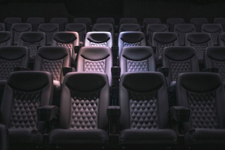 Rangées de fauteuils vides dans une salle de cinéma plongée dans la pénombre