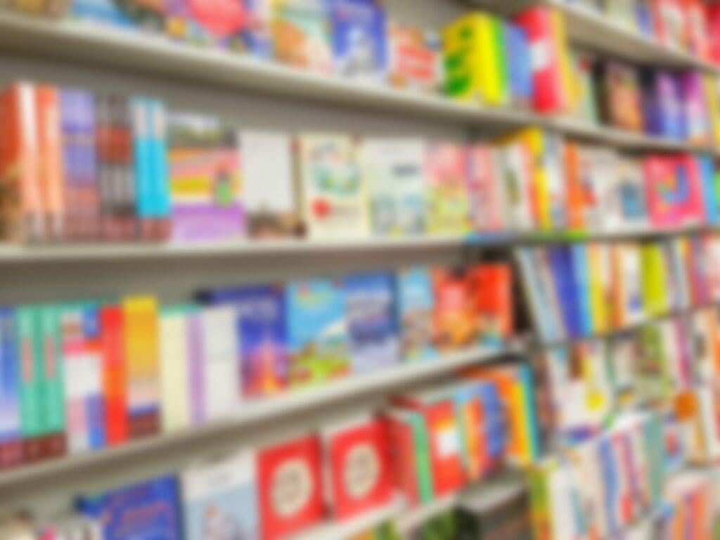 Rayonnages de librairie remplis de livres aux couvertures colorées, photographiés volontairement flous