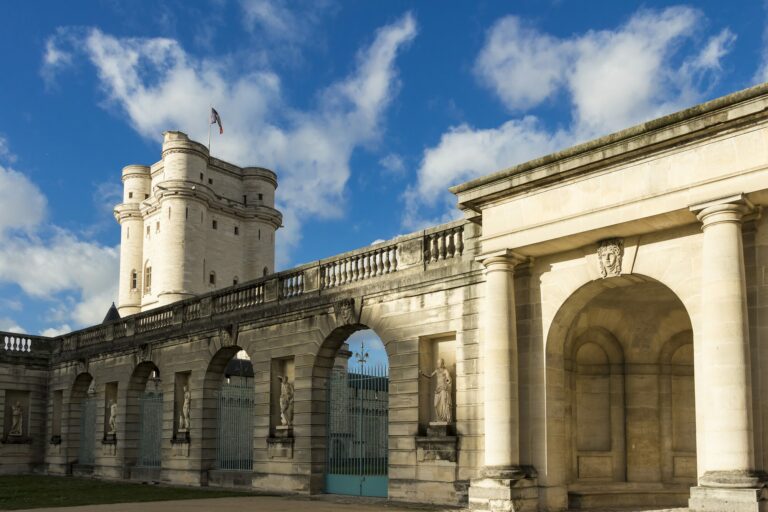Château de Vincennes avec sa tour et sa porte à arcades sous un ciel bleu nuageux