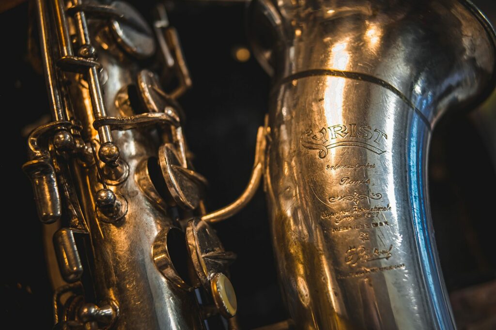 Gros plan sur deux saxophones anciens argentés aux reflets métalliques sur fond sombre