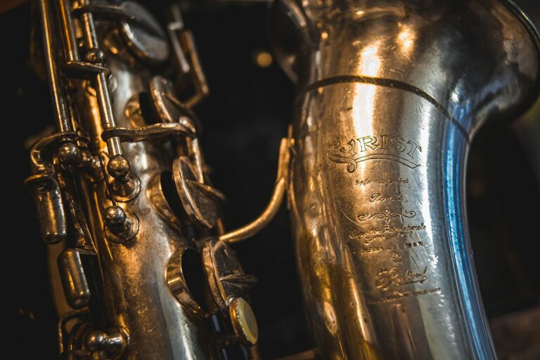 Gros plan sur deux saxophones anciens argentés aux reflets métalliques sur fond sombre