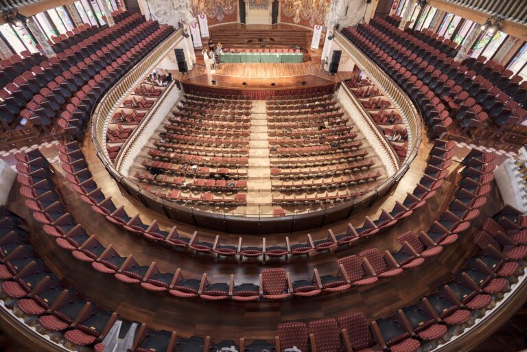 Salle de théâtre à l'italienne vue d'en haut, avec ses rangées de fauteuils rouges et ses balcons en fer à cheval disposés face à la scène