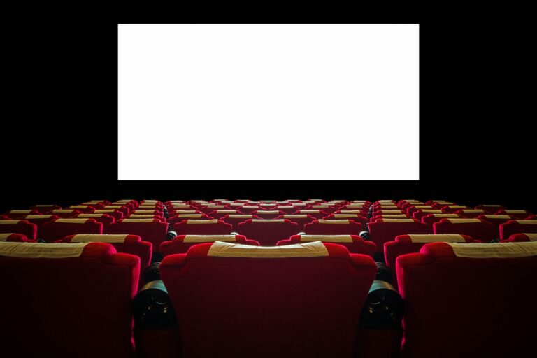 Salle de cinéma vide aux fauteuils rouges face à un grand écran blanc