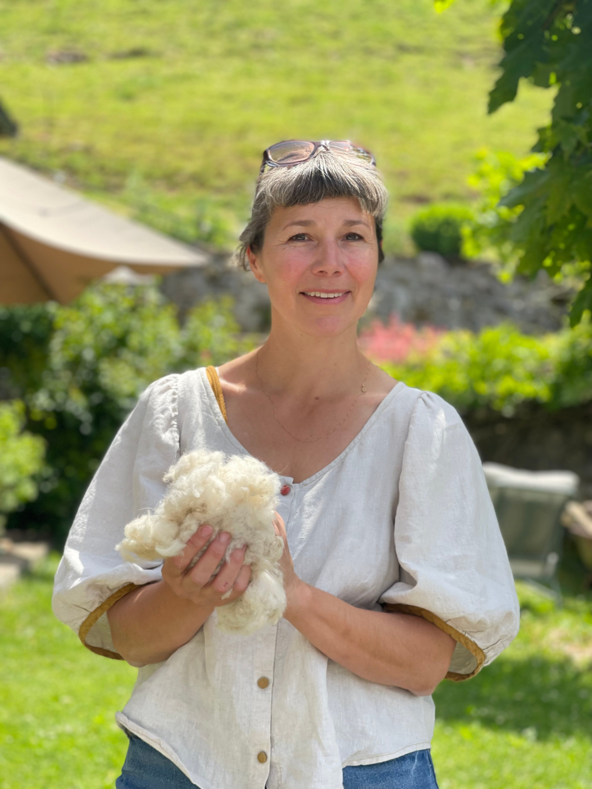 Portrait de Gaëlle Cornelis tenant une toison de cachemire dans son jardin