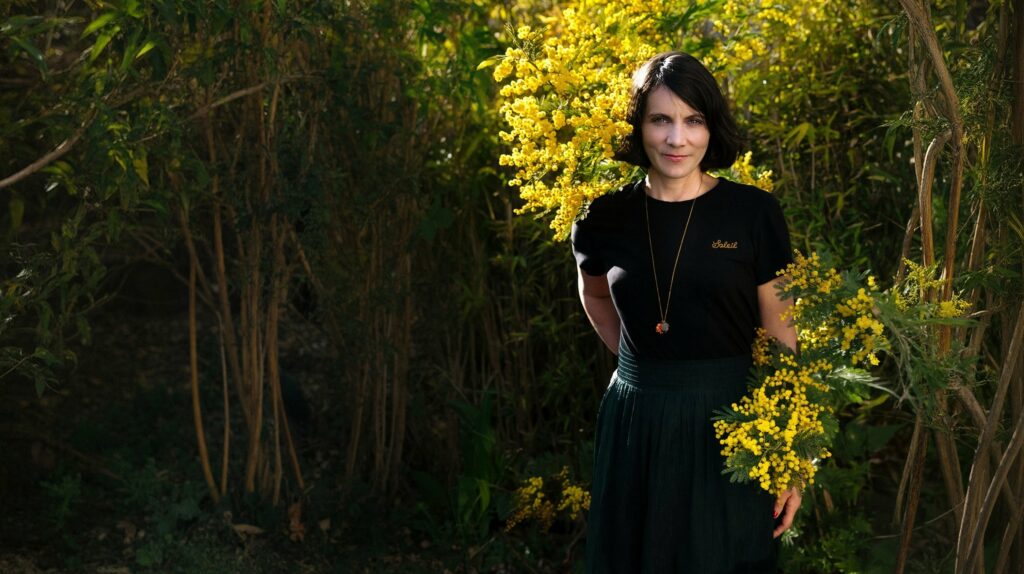 Muriel Brunier devant un mimosa en fleurs, format paysage