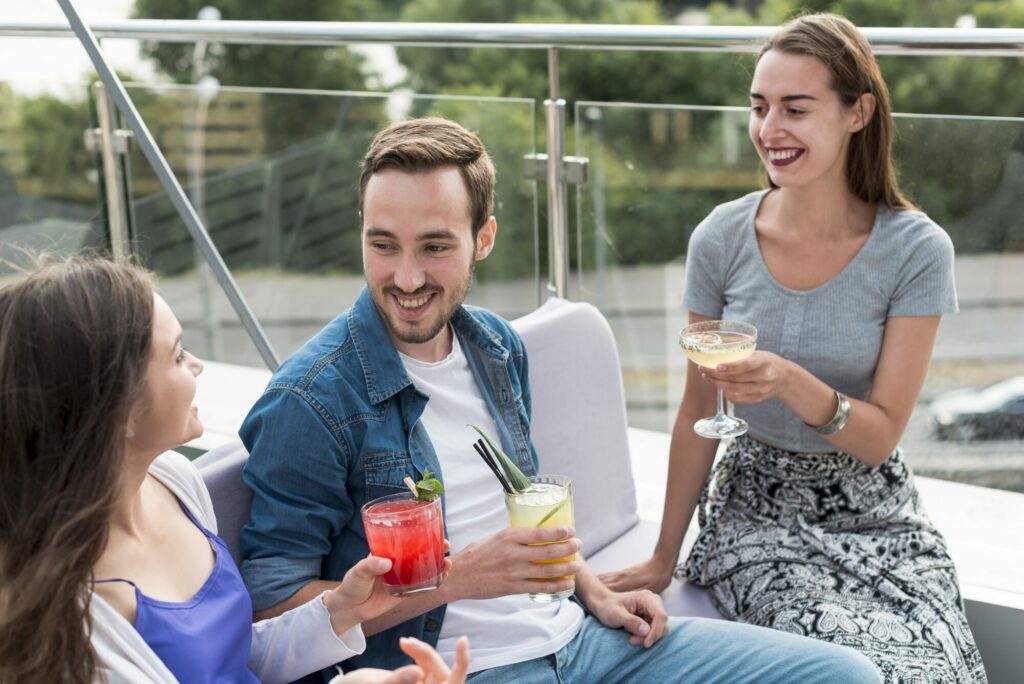 Trois amis souriants partagent un verre sur une terrasse en plein air
