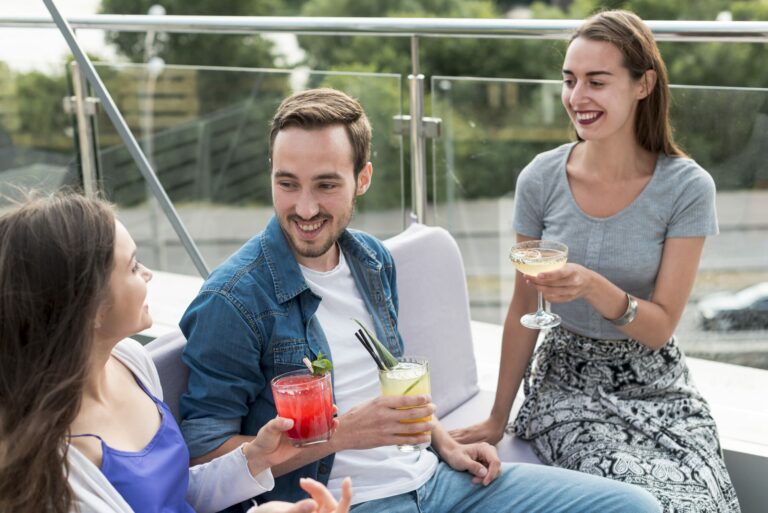 Trois amis souriants partagent un verre sur une terrasse en plein air