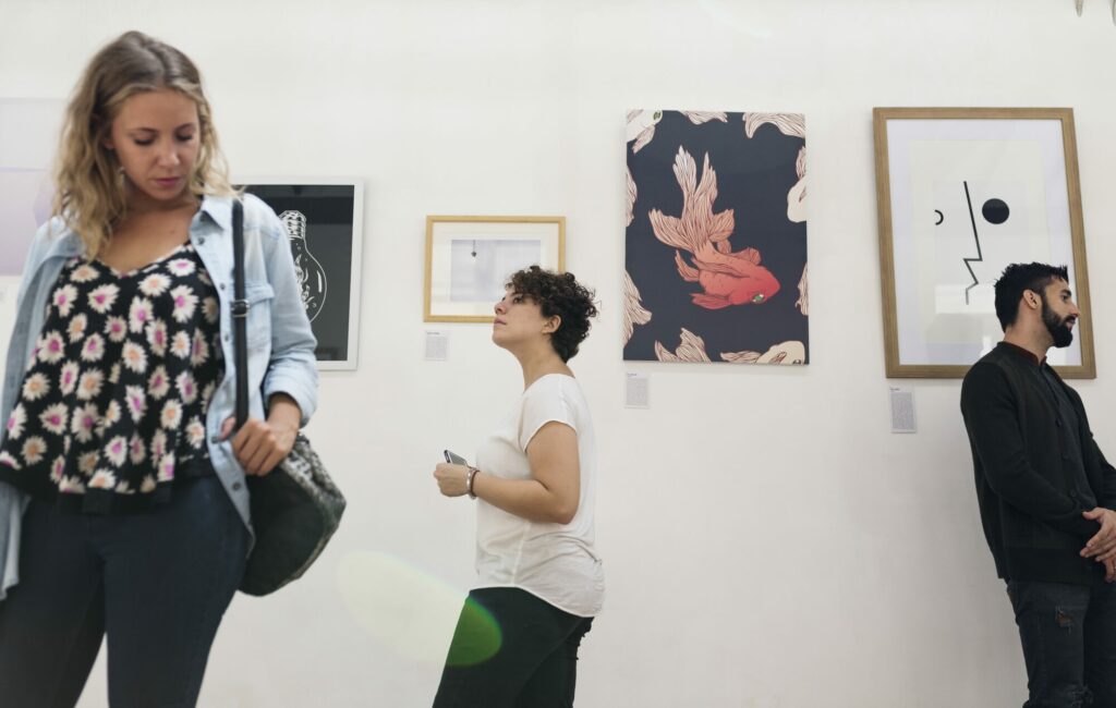 Visiteurs observant des tableaux accrochés aux murs blancs d'une galerie d'art