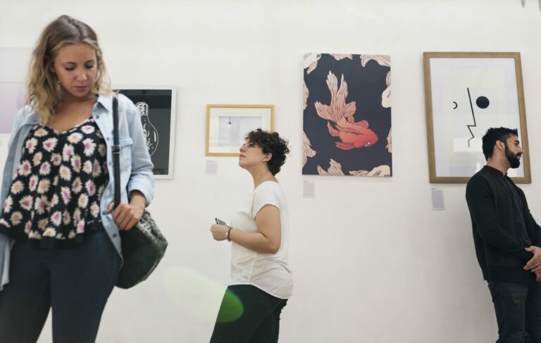 Visiteurs observant des tableaux accrochés aux murs blancs d'une galerie d'art