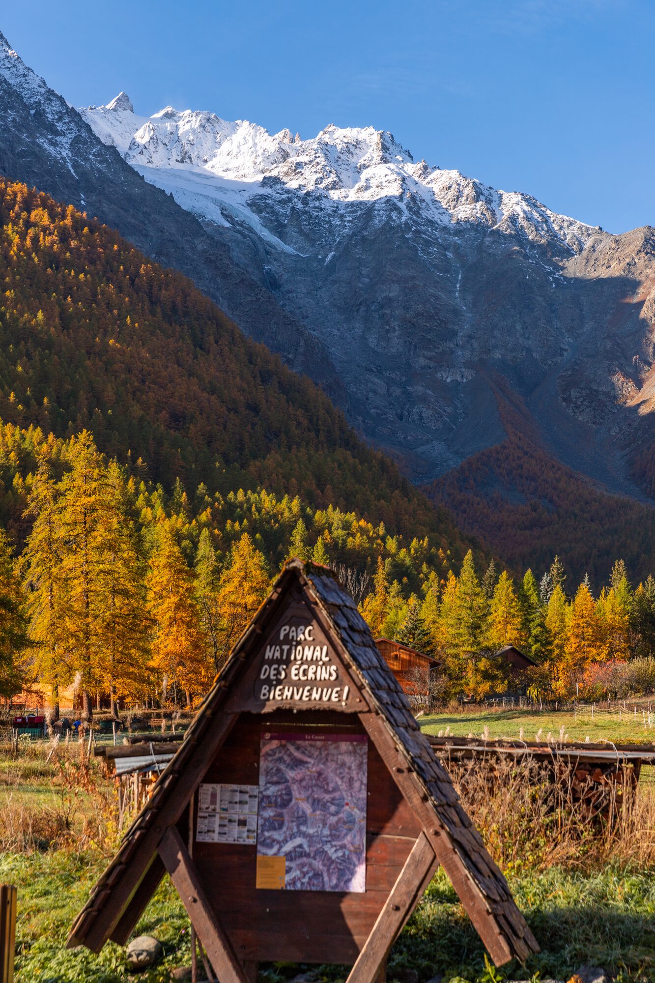Panneau d’entrée du parc national des Écrins sous les sommets enneigés