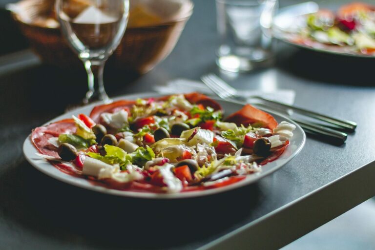 Assiette de salade composée et colorée servie sur une table de restaurant avec un verre de vin
