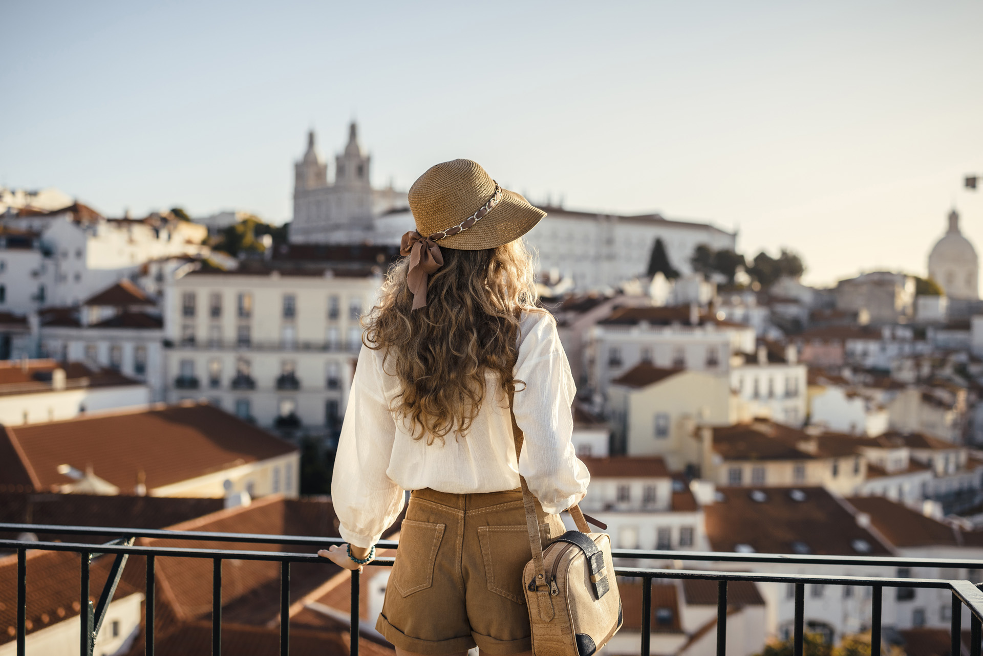 Jeune femme au chapeau de paille contemplant les toits d’une ville du sud