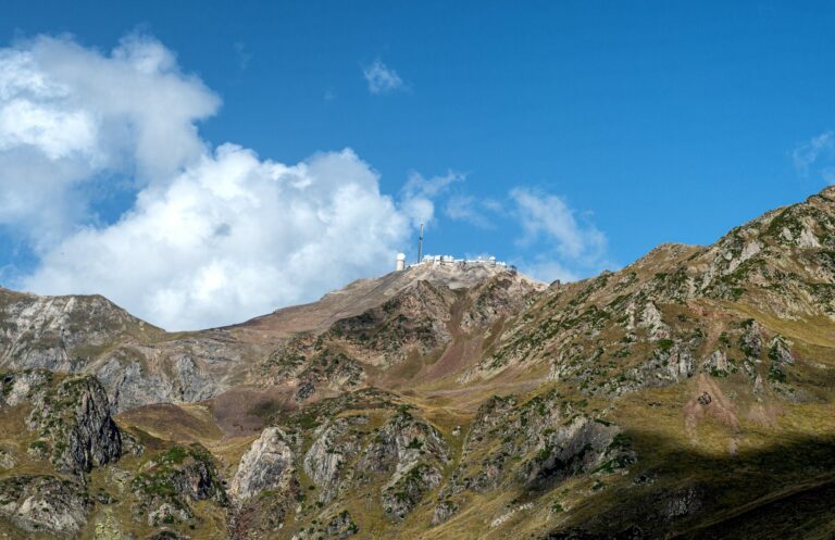 Versants rocheux du Pic du Midi de Bigorre sous un ciel bleu traversé de nuages blancs