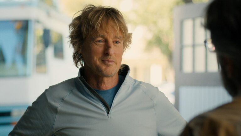 Owen Wilson en pull polaire gris, en extérieur sous le soleil, dans la saison 2 de la série Stick