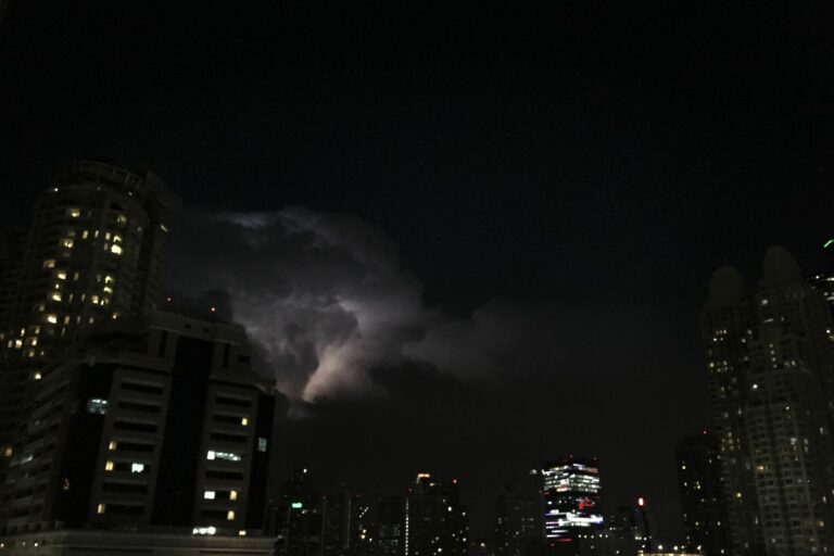 Ville plongée dans la nuit sous un ciel d'orage zébré d'un éclair