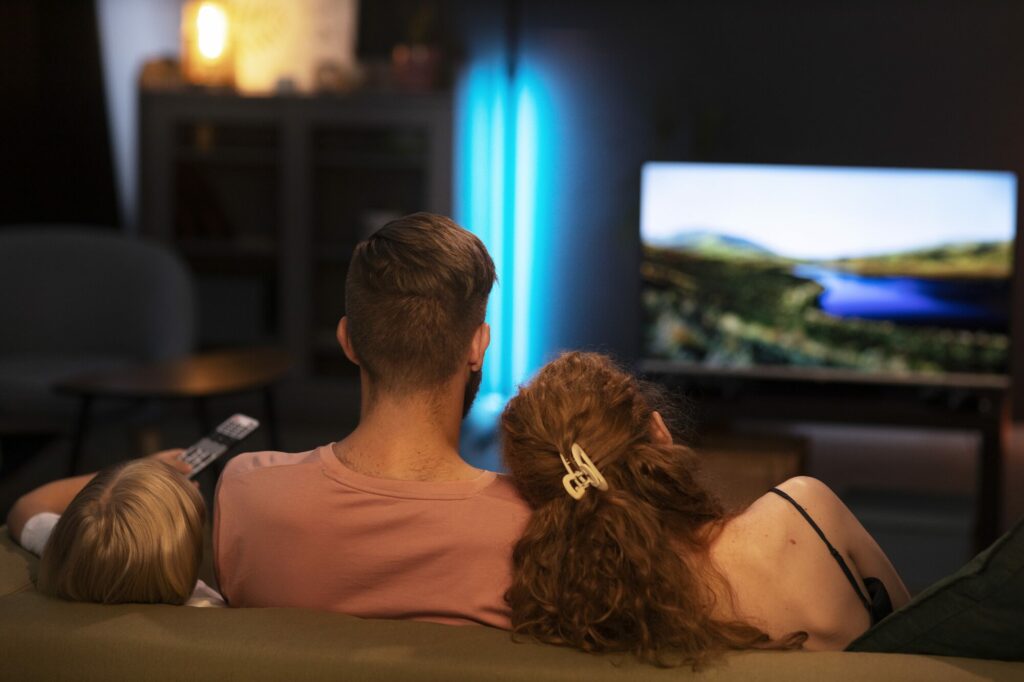 Famille vue de dos regardant un film sur un téléviseur dans un salon