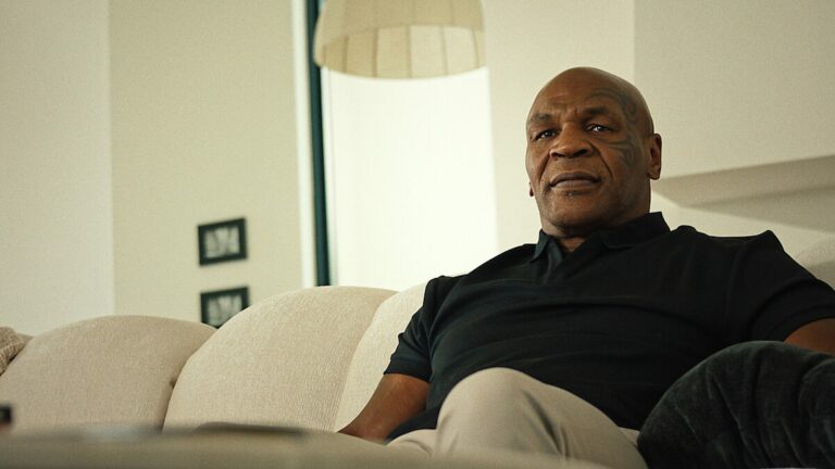 Mike Tyson assis sur un canapé clair dans un salon lumineux, dans la série documentaire TYSON
