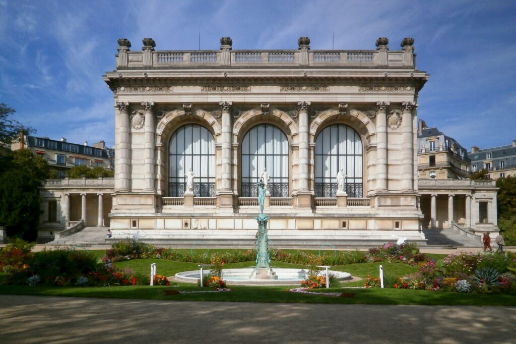 Façade à arcades du Palais Galliera et son jardin à Paris sous un ciel bleu